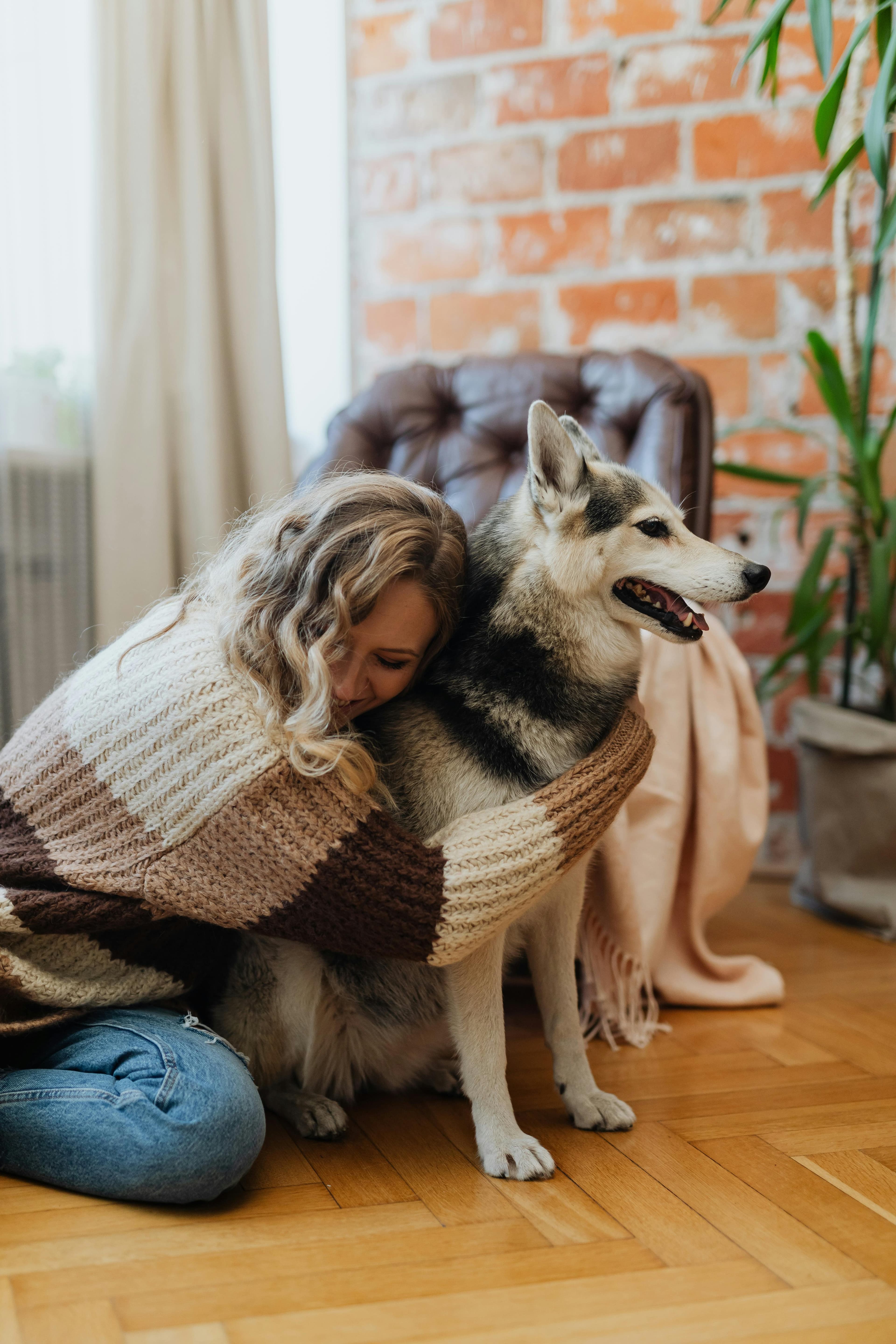 Una persona abbraccia il proprio cane in casa, in un momento caldo e rassicurante